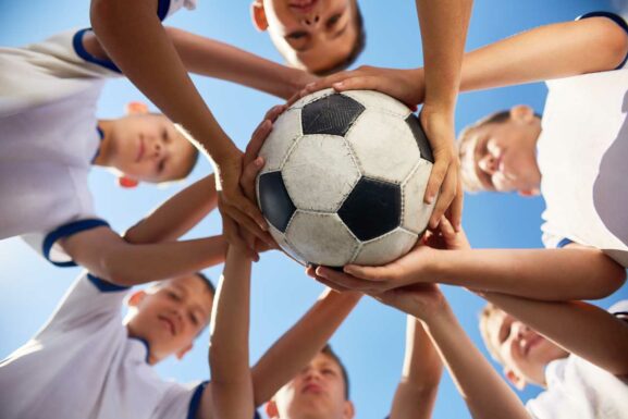 Sechs Kinder halten einen Fußball